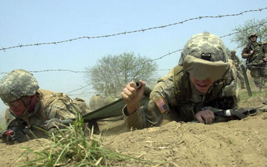 Sgt. Benjamin Woln, right, and 2nd Lt. Bennett Baldwin, both of the 2nd Infantry Division’s 302nd Brigade Support Battalion, carry a litter with two other soldiers under barbed wire at Warrior Base on Monday.
