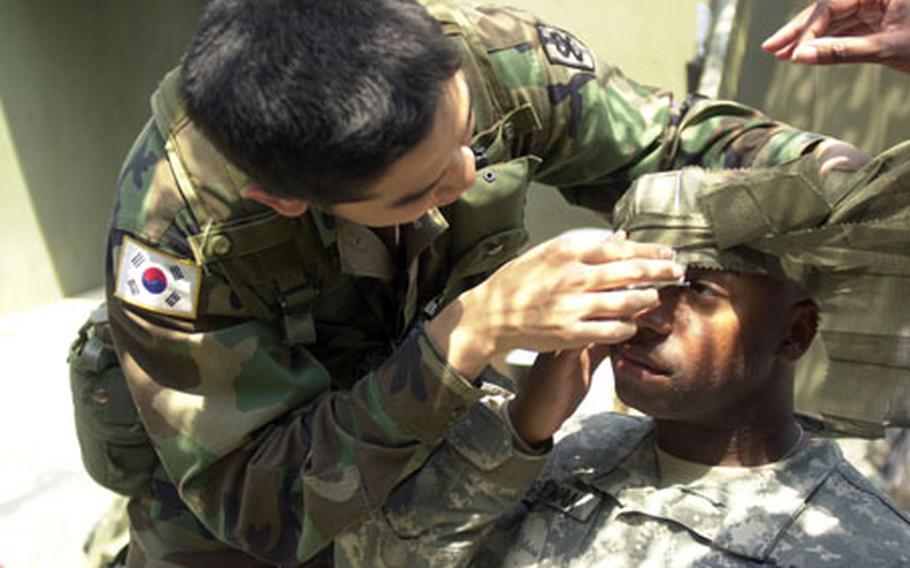 Cpl. Kim Hong-bun treats Staff Sgt. Jarroun Freeman’s mock eye wound during Expert Field Medical Badge orientation at Warrior Base Monday. Between five and 25 percent of soldiers who vie for the coveted badge typically pass the entire test.