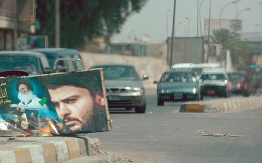 A picture of radical Shiite cleric Moqtada al-Sadr adorns the median in a street in eastern Baghdad as a U.S. military convoy drives by.