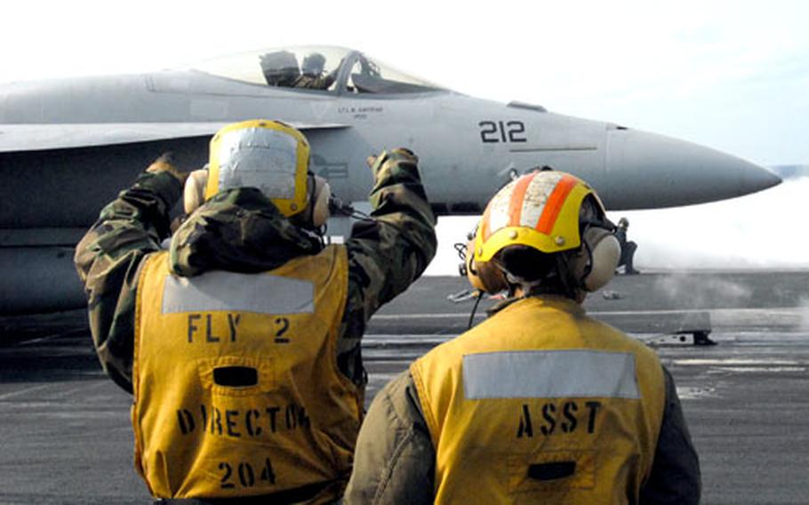 Sailors direct an F-18 pilot before takeoff on the flight deck of the USS Nimitz on Monday afternoon.