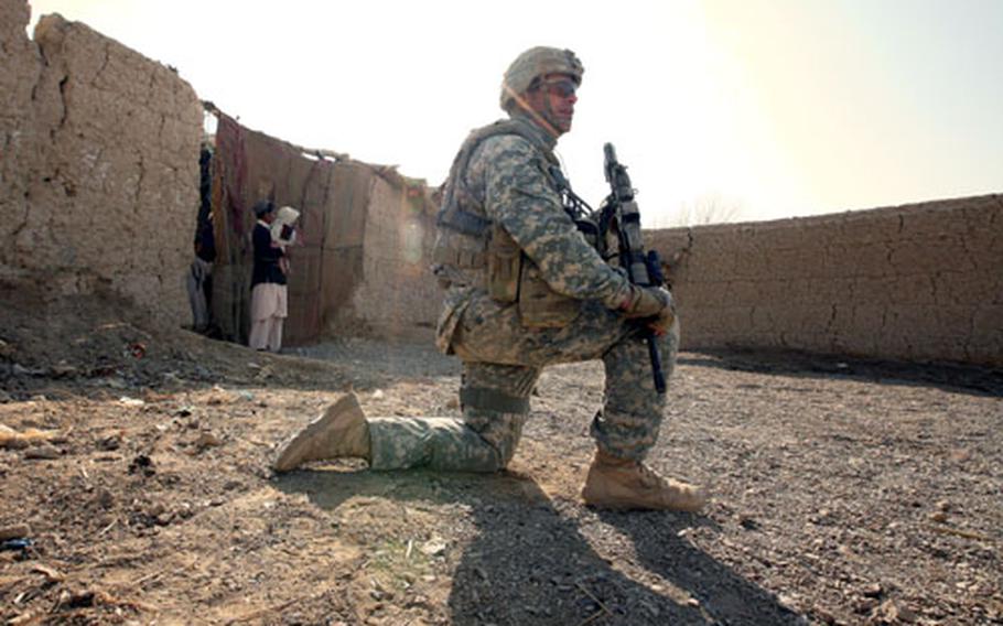 Staff Sgt. Jeff Ackerman, 41, a soldier with Company A, 2nd Battalion, 2nd Infantry Regiment, kneels and waits as other soldiers meet with an elder in the village of Mama Karez.
