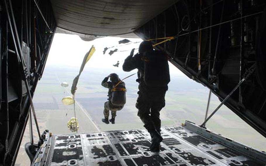 Bulgarian paratroopers jump from the open rear hatch of a C-130E, hands holding helmets and legs apart, during Operation Thracian Spring 2009 last week in Bulgaria.