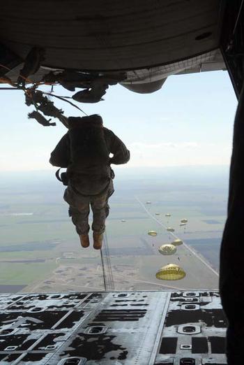 A U.S. paratrooper jumps from a C-130E aircraft with arms tightly in front of his body and feet together and forward during a static-line jump with Bulgarian paratroopers.