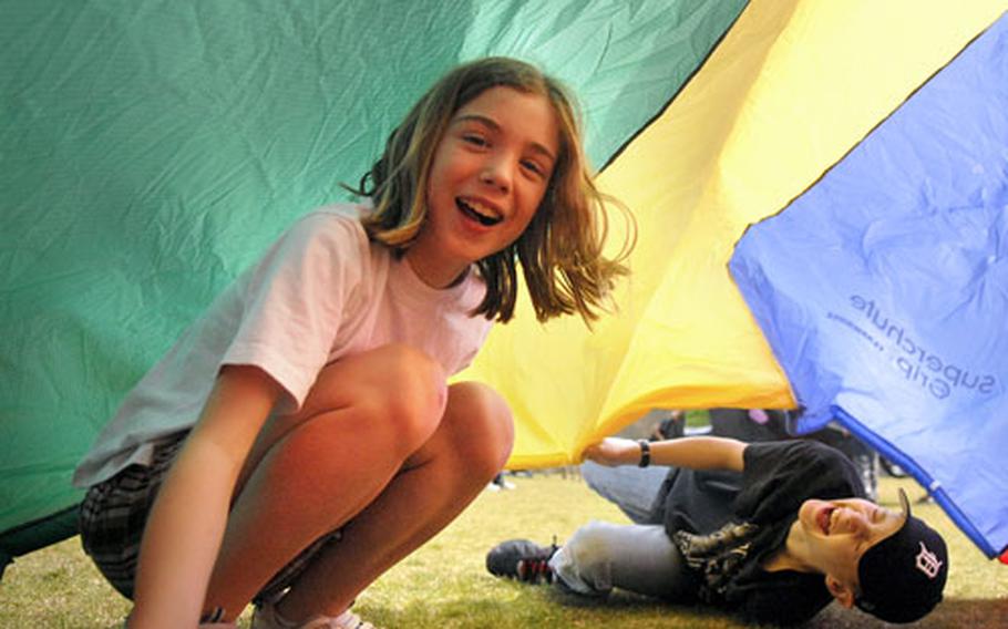 Sarah Brown, 10, and Tyler Britton, 12, react to the collapsing parachute Monday during the first day of B.R.A.T. adventure camp at Ramstein Air Base, Germany. Sixteen youngsters are spending their spring break kayaking, rock climbing and learning the fine art of teamwork during the event, put on by Outdoor Recreation.