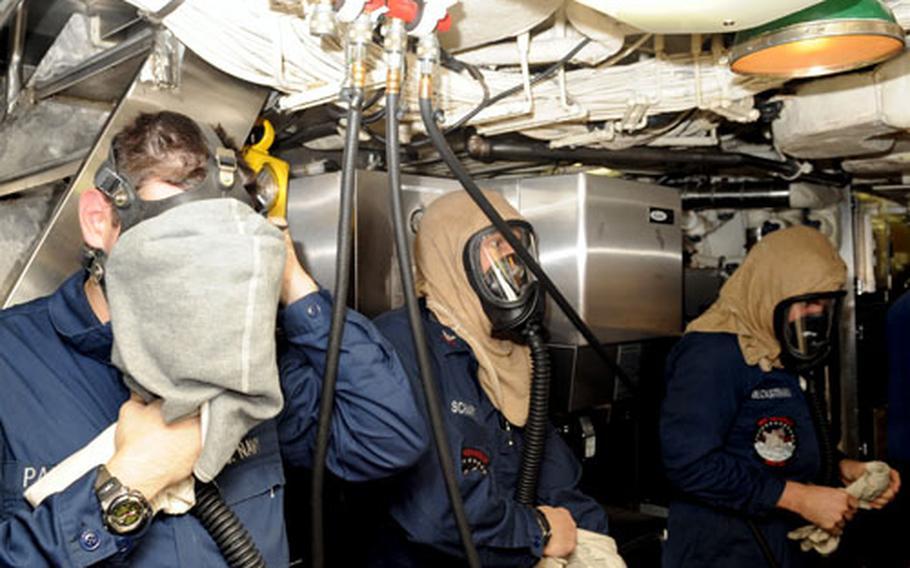 Petty Officer 3rd Class Jonathan Panciera, left, and petty officers second class Bryan Schartel and Kevin Beckstrand don their Emergency Air Breathing masks during a drill aboard the USS Seawolf on May 4. The connecting valves above them are located throughout the submarine, just in case the boat rapidly loses oxygen.