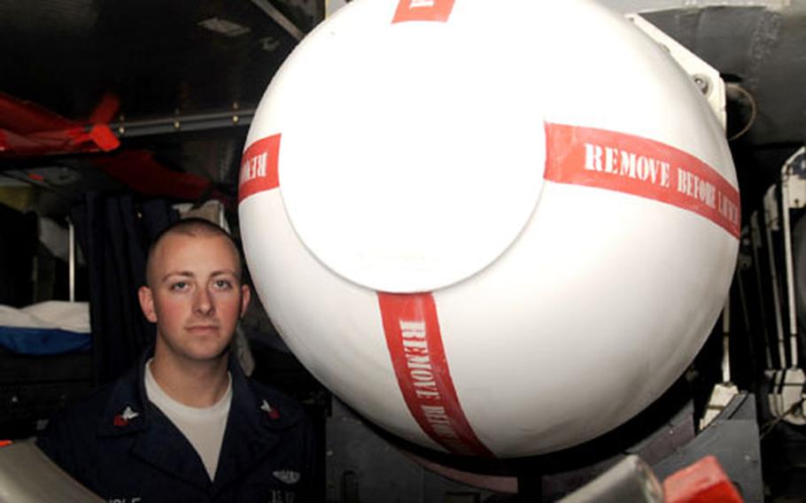 Petty Officer 1st Class Andrew Lisle stands between a Tomahawk cruise missile and the racks where several torpedomen sleep aboard the USS Seawolf.