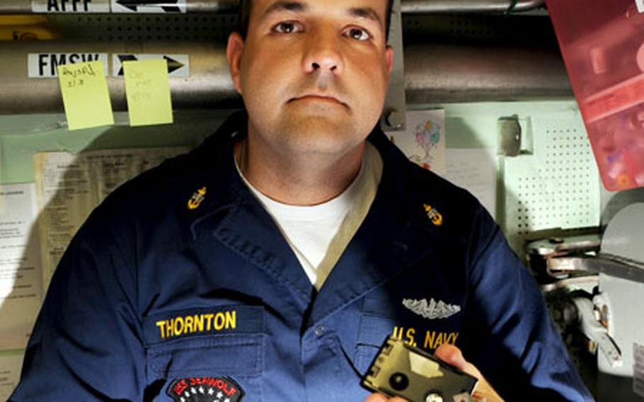 Chief Petty Officer and USS Seawolf medic John Thornton displays a dosimeter, which every sailor aboard wears to monitor radiation exposure. While dosimeters protect health, their readings are also highly documented to protect the Navy against potential medical lawsuits. Most submariners receive over the course of their careers the same amount of radiation exposure that transatlantic flight passengers would be exposed to, Thornton said.