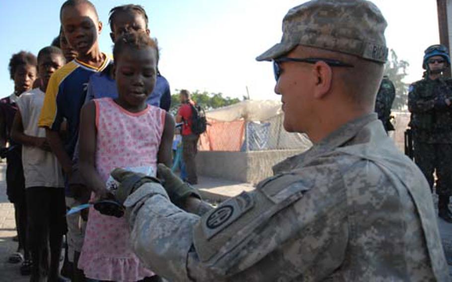 Sgt. Otis Richardson, Company A, 1st Battalion, 325th Airborne Infantry Regiment, hands out World Food Program high-calorie biscuits to children in Cite Soleil.