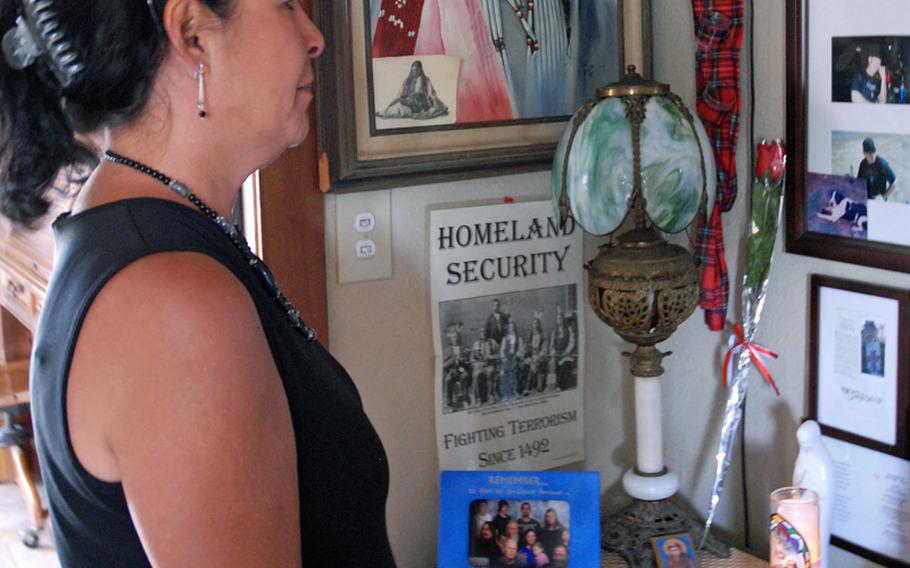 Looking at her family's memorial wall of photos in her Phoenix home, Jeanette Baker prays for her son, Army Sgt. Jonathan Hughey, who committed suicide Jan. 1. She turned to her Catholic faith to help her get through her grief as she searches for answers to why her son killed himself.