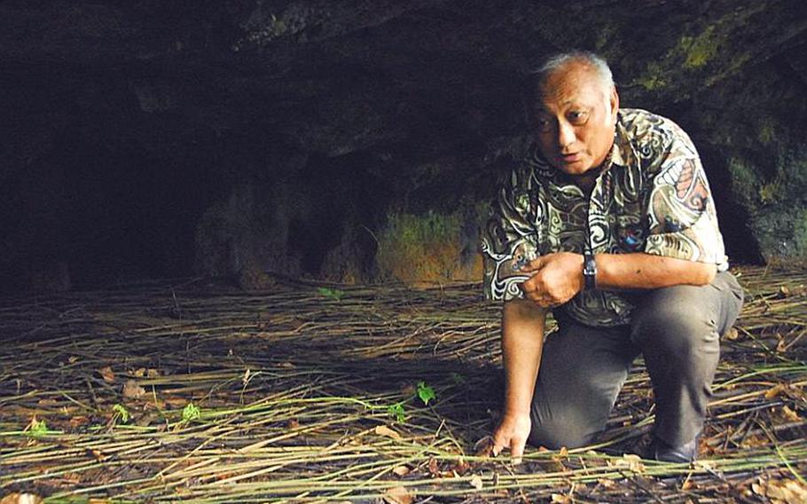 Chris Reyes, a World War II survivor, crouches in one of the caves where islanders, including his family, hid during the Japanese occupation of Guam.