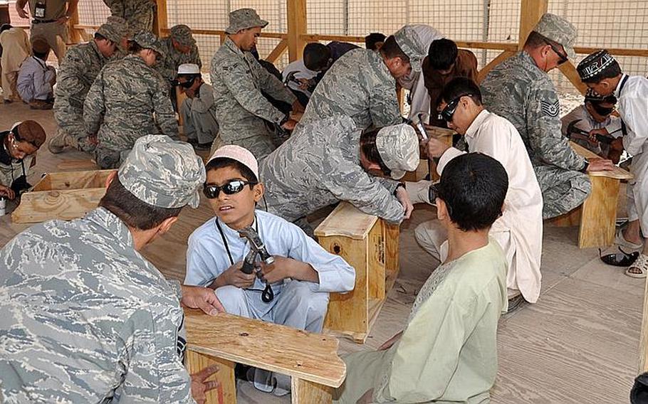 Boys from Kandahar, Afghanistan, learn how to build a shelf with help from the U.S. Air Force earlier this year. In the absence of civilian aid workers, the U.S. military must deviate from fighting to take on humanitarian and community building jobs.