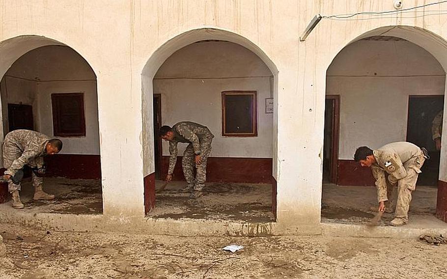 U.S. soldiers with Company B, 2nd Battalion, 508th Parachute Infantry Regiment and a Canadian soldier with a psychological operations team sweep up in a compound in the village of Deh-e-Kuchay where the troops set up an Afghan police outpost.