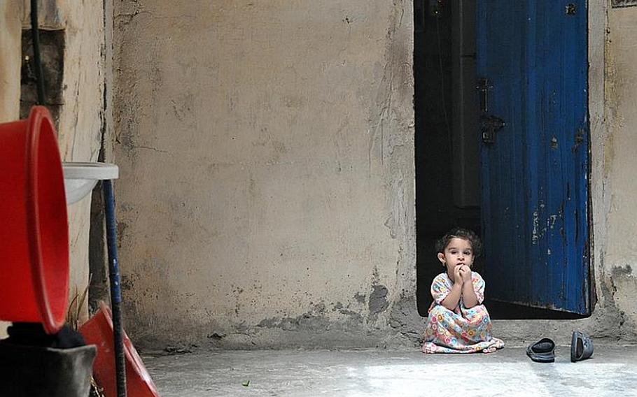 Little Bdoor, sits in the doorway of the room she lives in, in downtown Baghdad.