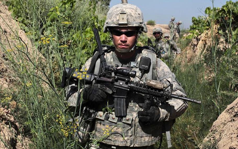 Sgt. Mitchel Stallings, of Troop B, 1st Squadron, 71st Cavalry Regiment, and other troops move through an irrigation trench in a grape orchard in Dand district, Kandahar province, Afghanistan on June 19.