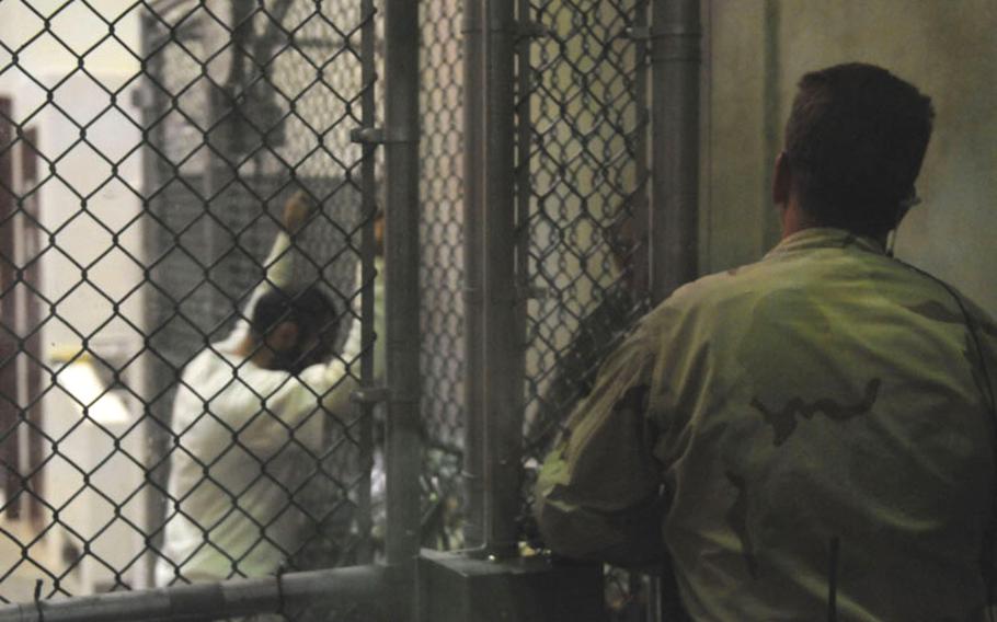 A sailor assigned to the Navy Expeditionary Guard Battalion stands watch over a cell block in Camp 6 at Joint Task Force Guantanamo while detainees look through magazines and books in this March 2010 photo. All detainees arriving at Guantanamo are administered a large dosage of the controversial anti-malarial drug mefloquine, regardless of whether they exhibit symptoms of the disease.