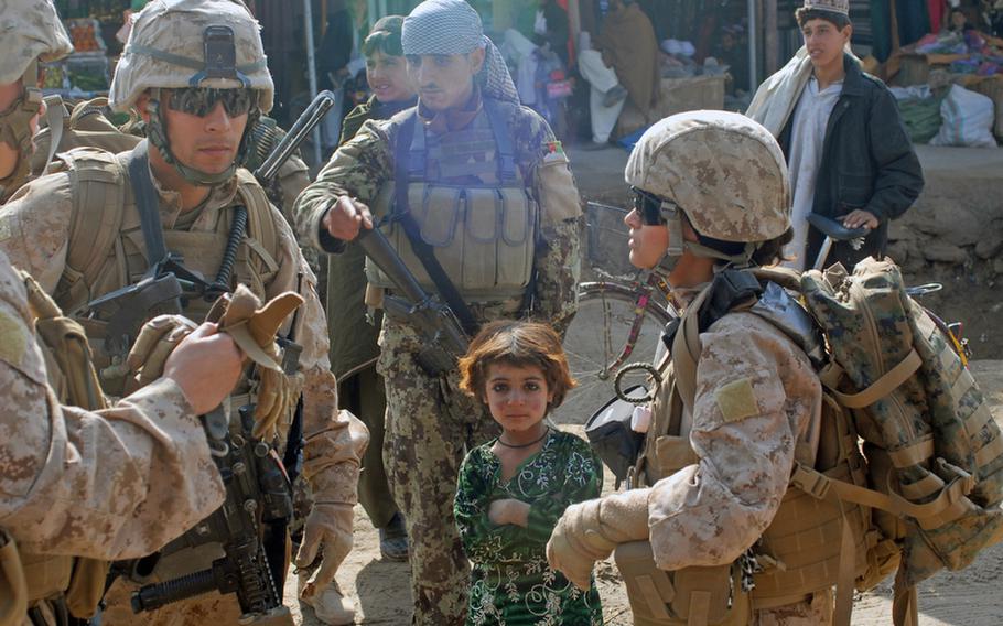 Heela Nasseri, an interpreter with a Marine FET in Marjah, explains to the Marines that a surly Afghan soldier along for the mission had been interfering with her engagement with children in the bazaar, and that she refused to continue the mission if the soldier, wearing the head scarf, stayed on.