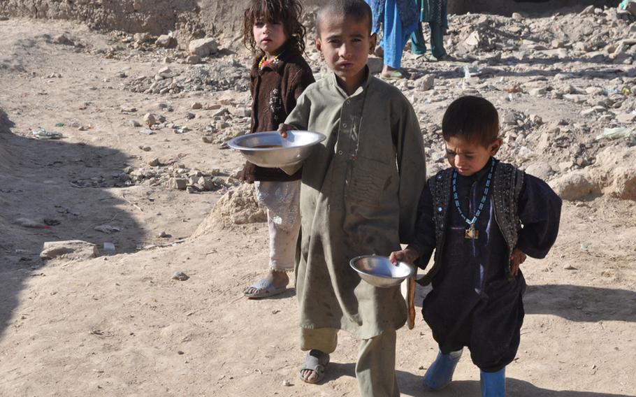 Children at the Charah-e-Qambar camp for displaced persons on the outskirts of Kabul clutch lunch distributed by an international aid agency on Dec. 13.