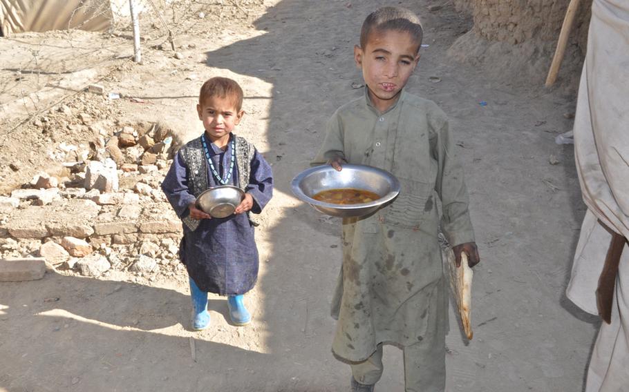 Children at the Charah-e-Qambar camp for displaced persons on the outskirts of Kabul clutch lunch distributed by an international aid agency on Dec. 13.