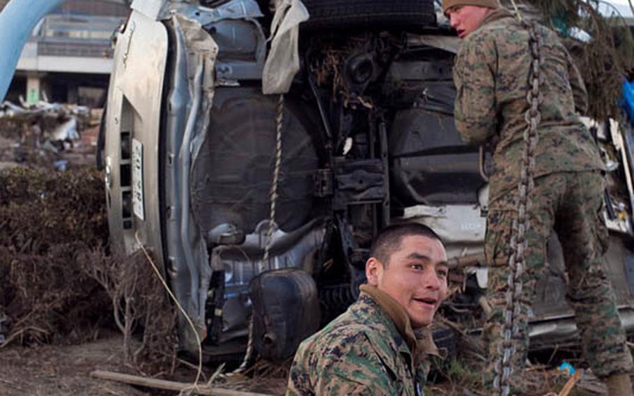 Marine Corps Staff Sgt. Hugo Roman, foreground, and Lance Cpl. Kyle White from Camp Fuji have assist in the clearing of Sendai Airport in Sendai, Japan, that was severly damaged after a 9.0 earthquake and resulting tsunami hit the area. U.S. forces have cleared the runway of hundreds of wrecked cars and other debris enabling the airport to receive humanitarian aid.