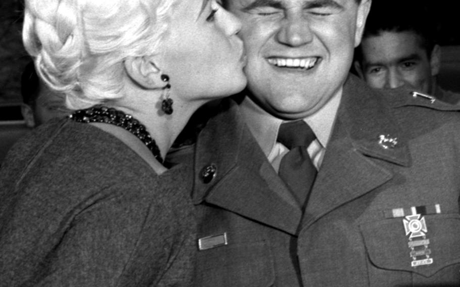 A servicemember who won a contest collects his prize, a kiss from Jayne Mansfield. The actress had just arrived at Rhein-Main from Paris to begin a six-day visit to Germany that included visits to a military hospital, a service football game and an officers' club reception. At an airport press conference, she announced her plans to marry Hungarian body-builder Mickey Hargitay.