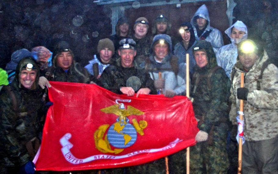 Only 26 members who started the climb made it to the summit, and a small group pose here for a photo while holding a U.S. Marine Corps flag.