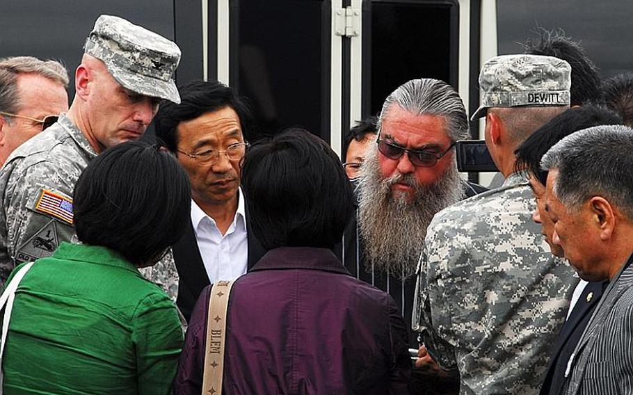 Steve House, center, studies a map of Camp Carroll&#39;s helipad area and discusses where he believes he buried barrels of Agent Orange in 1978. Surrounding him are South Korean lawmakers and members of a joint U.S.-South Korean task force who are investigating his claims. Standing near House is Col. Joseph Birchmeier, a U.S. Forces Korea engineer.
