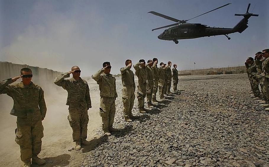 Soldiers from Company C and Scout Platoon, 1st Battalion, 32nd Infantry Regiment, 3rd Brigade Combat Team, 10th Mountain Division salute as soldiers killed in an improved explosive device strike are flown from Combat Outpost Nalgham to Kandahar Air Field in Afghanistan on August 11, 2011.