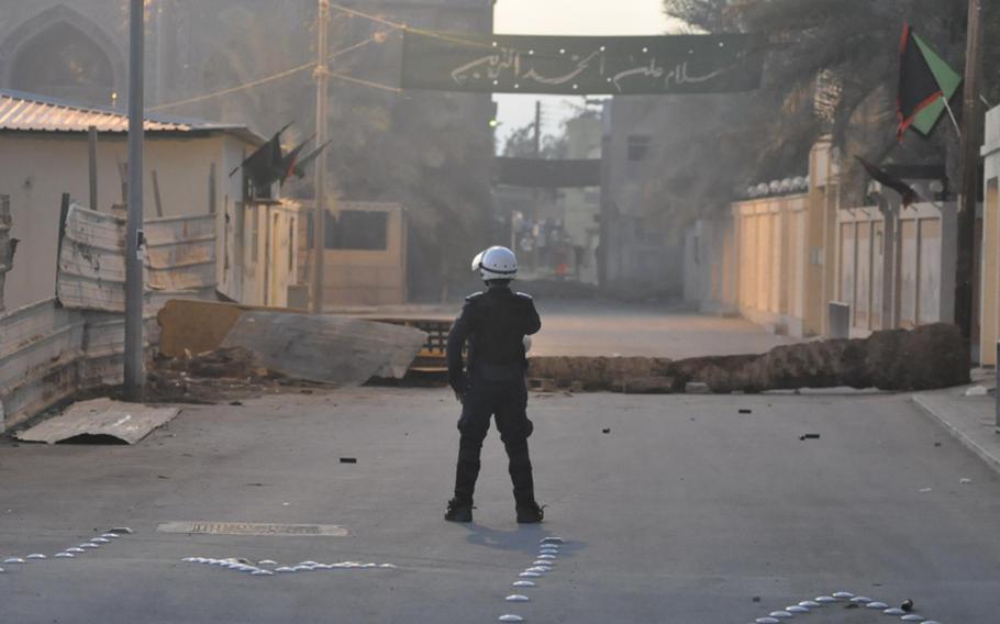 A policeman stands near a makeshift barricade on Dec. 22 in the Abu Seba village of Bahrain, a tiny Persian Gulf nation that has seen a wave of unrest since last year. The al-Khalfia regime has pledged democratic reform, but in recent months the police have taken a more heavy-handed approach with protesters. Oftentimes, protesters in the poorest Shia areas will block the road to prevent the police from entering with their trucks.