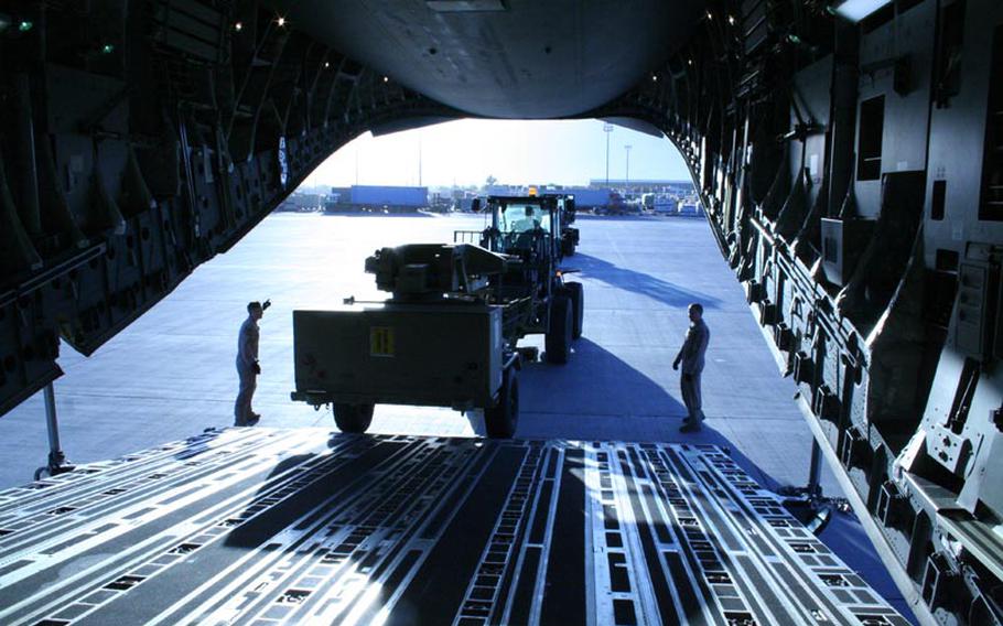 Staff Sgt. Eric Bratton, left, directs a forklift unloading an Army satellite communications truck from an Air Force cargo plane on May 12, 2012, at Bagram Air Field, Afghanistan.
