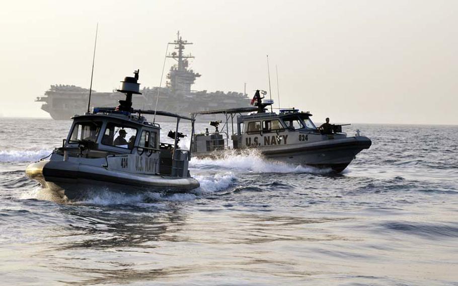 Sailors assigned to Maritime Expeditionary Security Squadron 5 and MSRON 9 escort the aircraft carrier USS Carl Vinson through the Arabian Gulf on March 25, 2011. 