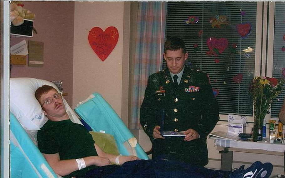 Erik Schei, receives a purple heart from his squad leader in January 2006 at the VA polytrauma center in Minneapolis, where he was recovering from a gunshot wound to the head. Only skin covers his brain, as most of his skull was removed.