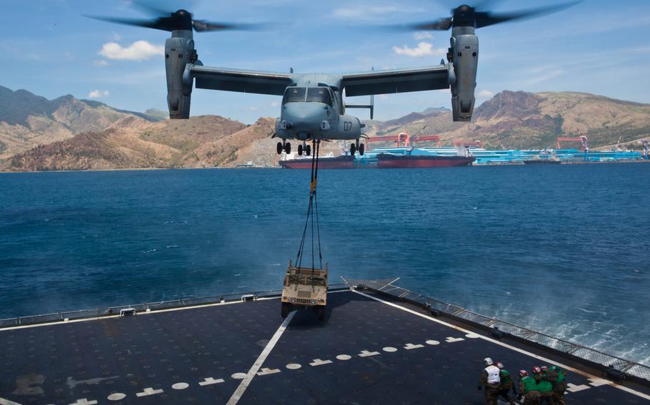 Landing support specialists back away after connecting a Humvee to a U.S. Marine Corps MV-22B Osprey during external lift training at Subic Bay, Philippines, during exercise Freedom Banner 2013. The training was the first time an Osprey has conducted an external lift with the Sacagawea.