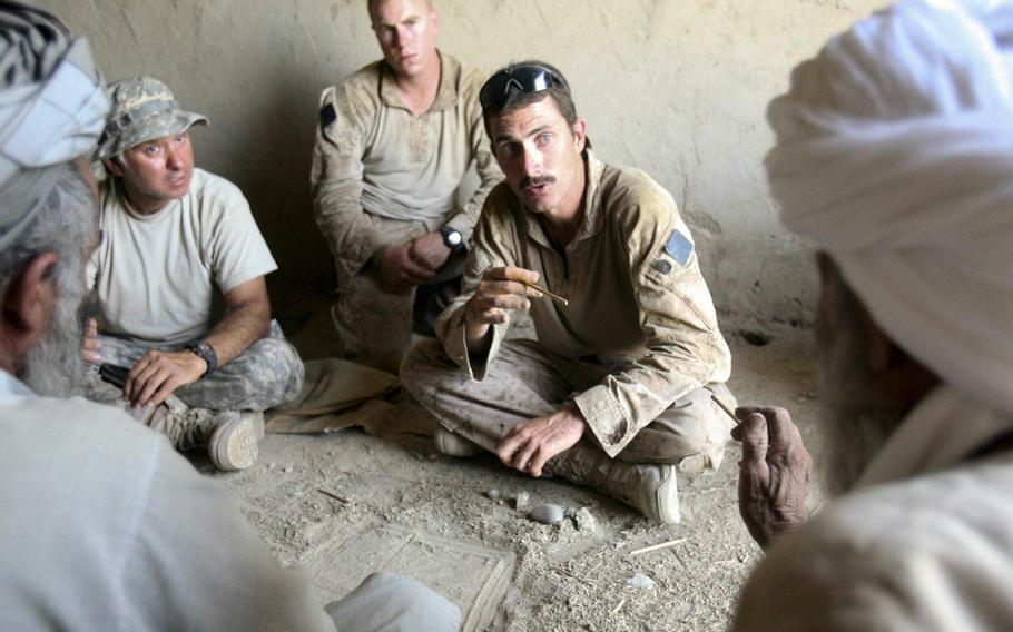Gunnery Sgt. Shawn Hughes talks with two local Afghan men at Patrol Base Fielder Sept. 14, 2009. Hughes, 31, is the scout sniper platoon sergeant from Roseburg, Ore., deployed with 1st Battalion, 5th Marine Regiment. Marines are using the property as a base for conducting security patrols in the area.
