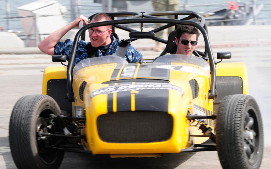 A sailor assigned to USS Typhoon takes a ride in a Caterham sports car April 17, 2013, with American F1 driver Alexander Rossi of Caterham Racing. Rossi spent the day with U.S. Navy units in Bahrain and will be racing at the Formula One Gulf Air Bahrain Grand Prix 2013, April 19.