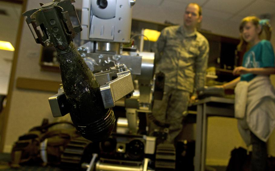 Senior Airman Jeff Butera, of the 48th Explosive Ordnance Disposal Flight, and 9-year-old Thayer Brown watch a bomb disposal robot as it picks up a shell during Job Shadow Day at RAF Lakenheath, England, on Friday, April 19, 2013. EOD members gave a presentation about their jobs and responsibilities as part of the job shadow event, which gave children a chance to learn more about the U.S. Air Force.