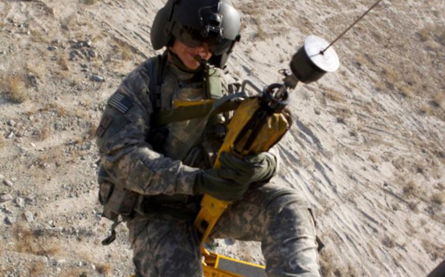 Julia Bringloe gtst lowered in a jungle penetrator hoist above the grounds in Afghanistan.