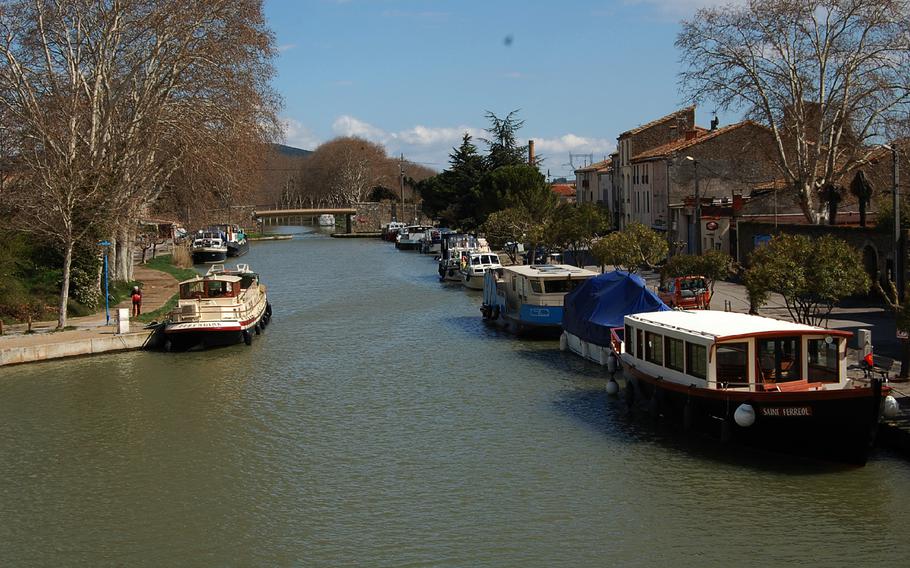 Boats line the Canal du Midi in the tiny town of Homps, France, which is a busy canal boat base in the summer. There are a few restaurants, shops and access to fresh water along the banks of the canal.