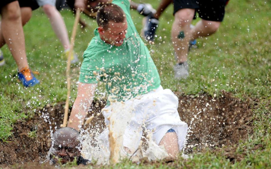 Participants fall into the mud pit during the 39th Air Base Wing Sports Day tug-of-war event May 24, 2013, at Incirlik Air Base, Turkey. Airmen from several squadrons competed in friendly games of volleyball, softball, basketball, kickball, dodgeball and tug-of-war.