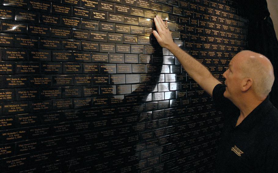 Retired Col. Steve Mahoney touches the name of the fallen colonel with whom he served. He was visiting a tribute wall for servicemembers killed after 9/11 in San Francisco in May.