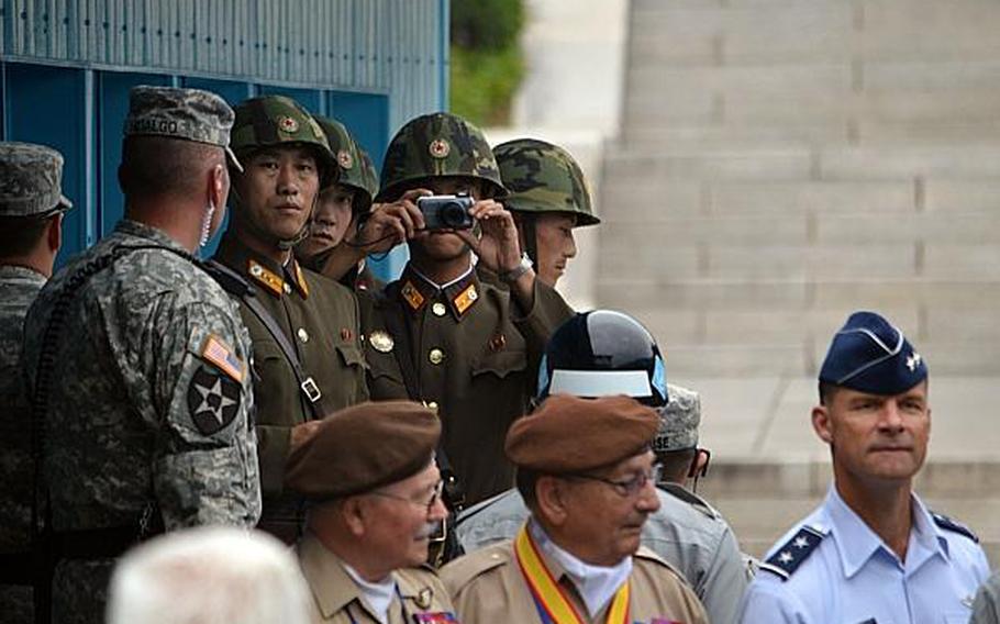 A North Korean soldier takes photos of the 21-nation delegation gathered at the demarcation line between North and South Korea at the Joint Security Area, South Korea, July 27, 2013. 
