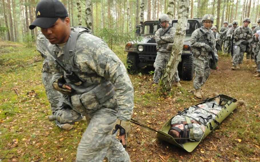 Sgt. Willard Wilson, a member of the U.S. Army's Bavaria Dental Activity, demonstrates how to pull a casualty on a rescue stretcher on Sept. 11, 2013, for candidates hoping to earn the Army Expert Field Medical Badge at Grafenwöhr Training Area in Germany.