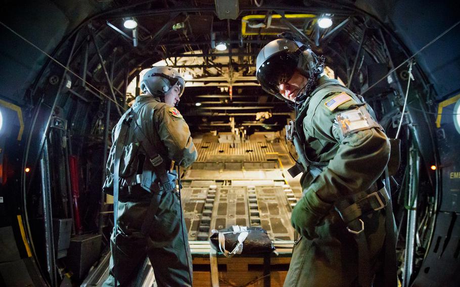 Airman 1st Class Andrew Fox, left, and Tech. Sgt. Todd Bergin, loadmasters assigned to the 36th Airlift Squadron, secure their harnesses before releasing a low-cost, low-altitude cargo bundle during a training mission over Yokota Air Base, Japan, on Oct. 8, 2013.