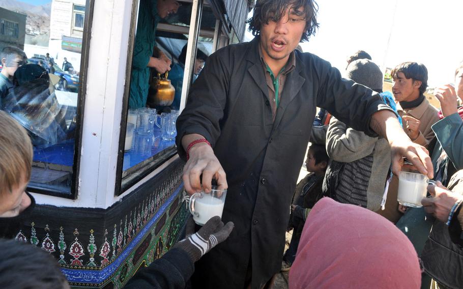 A man hands out hot, sweet milk to children Thursday after Ashura services at the central mosque in Bamiyan, Afghanistan.