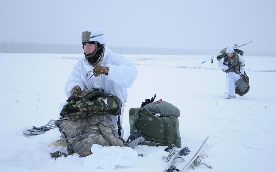Spc. William Baker, left, an infantryman with 4th Infantry Brigade Combat Team (Airborne), 25th Infantry Division, secures his equipment in preparation to move after jumping from a C-130 Hercules on Dec. 12, 2013 at the Malemute Drop Zone at Joint Base Elmendorf-Richardson, Alaska.