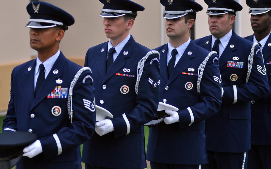 Members of the 31st Fighter Wing's base honor guard stand ready to place a hat from the Army, Navy, Air Force, Marine Corps and Coast Guard at a table designated for fallen or missing comrades during a ceremony to honor prisoners of war and missing in action Oct. 3, 2013, at Aviano Air Base, Italy.