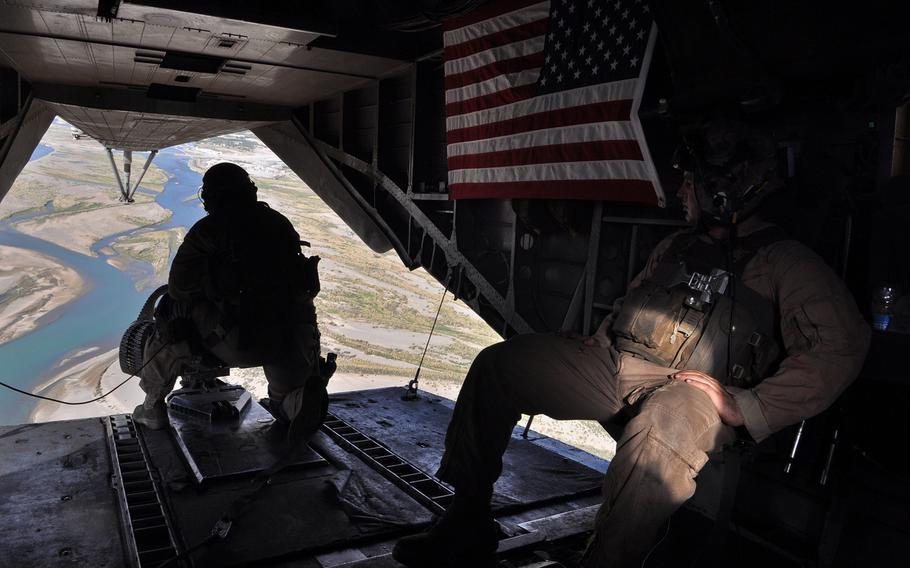 Sgt. Caleb Dye, left, and Sgt. Travis Eideh scan the landscape from the back of a helicopter flying out of Forward Operating Base Jackson, Afghanistan, in May 2013. The desert below, Sangin district, had become a symbol and a flash point for the insurgents, Afghan government and NATO coalition forces.