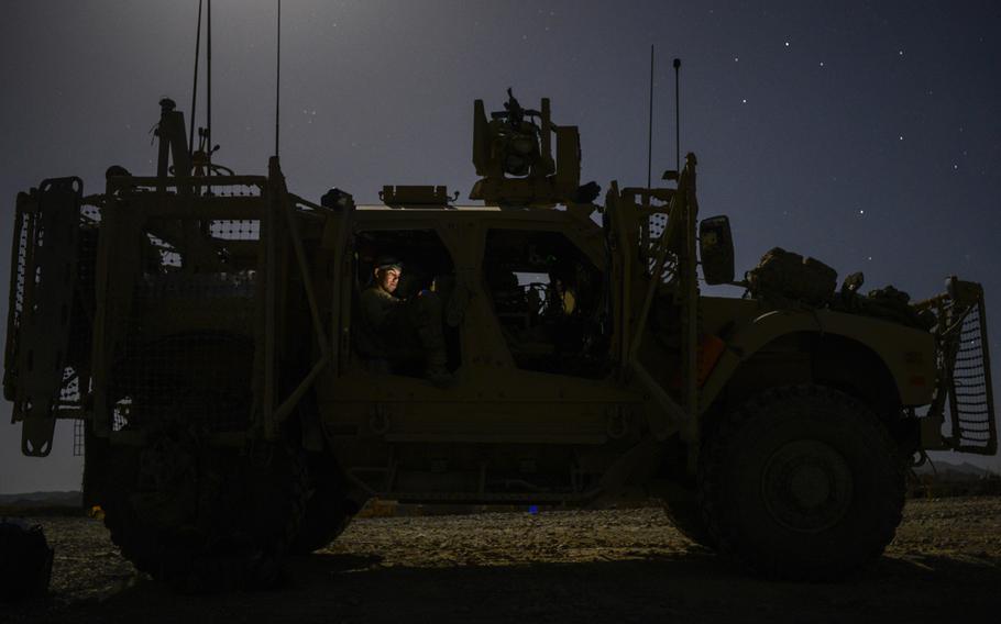 Staff Sgt. Shayne Laflin, with the 3rd Brigade, 1st Infantry Division, looks at photographs of his 7-month-old daughter on an iPhone inside an MRAP all-terrain vehicle at what used to be Forward Operating Base Sweeney in a remote corner of southern Afghanistan's Zabul province.