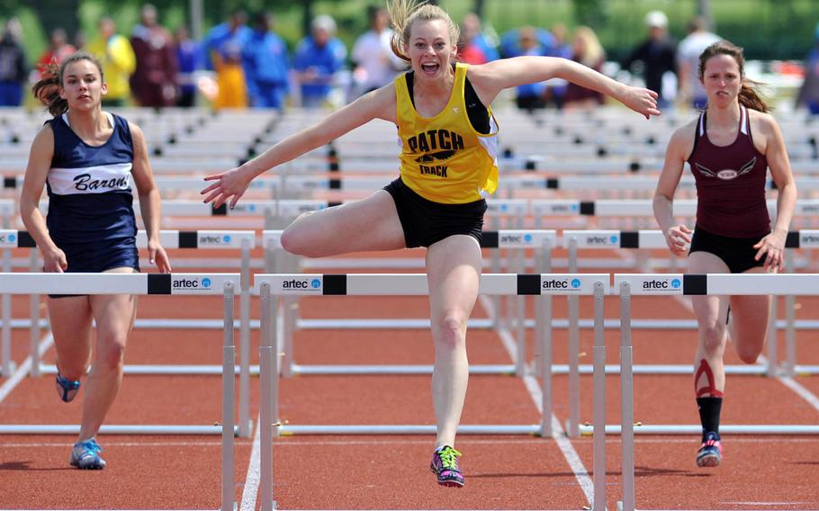 Patch's Abigail Peterson is all smiles as she clears the final hurdle on her way to winning the 100-meter hurdles at the DODDS-Europe track and field championships, May 25, 2013. At left is Bitburg's Brettina Thomas who finished fourth and third-place finisher Amber Rose of Vilseck is at right.