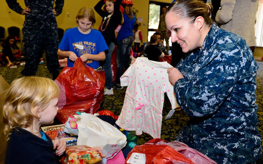 Personnel Specialist 1st Class Tina Cook opens gifts with an elementary student during the Naval Surface Warfare Center Panama City Division's 64th annual Children's Christmas Party Dec. 12, 2013. The division hosts the Children's Christmas Party as part of its community outreach program. 

