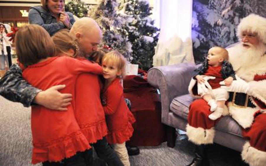 Fire Controlman 1st Class Chad Chambers hugs his daughters after surprising them with his homecoming while they were visiting Santa Claus at the MacArthur Center in Norfolk, Va., Dec 13, 2013. Chambers had been deployed aboard USS Stout since August and returned home early to transfer from the command and report to a shore duty command as part of a routine rotation.
